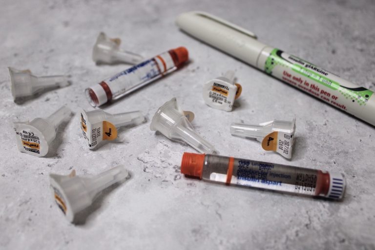 T1D supplies scattered around, including long-acting, quick-acting insulin and needle heads.