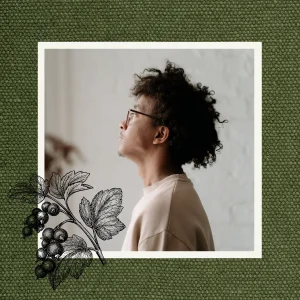 Man with curly hair looking towards the light, framed against textured green fabric with a botanical illustration.