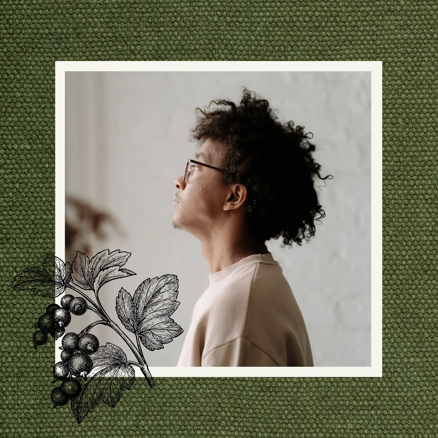 Man with curly hair looking towards the light, framed against textured green fabric with a botanical illustration.