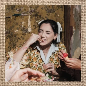 Woman enjoying food at a table, surrounded by hands sharing a meal, in a textured editorial frame.